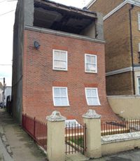 An art installation featuring a curved red-brick building with two rows of windows