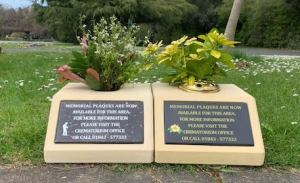 Two kerb memorials side by side with plaques and flowers