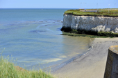 Blue sea with a sandy beach and white cliffs in the distance