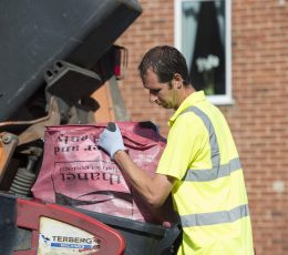 Male worker emptying red recycling bag