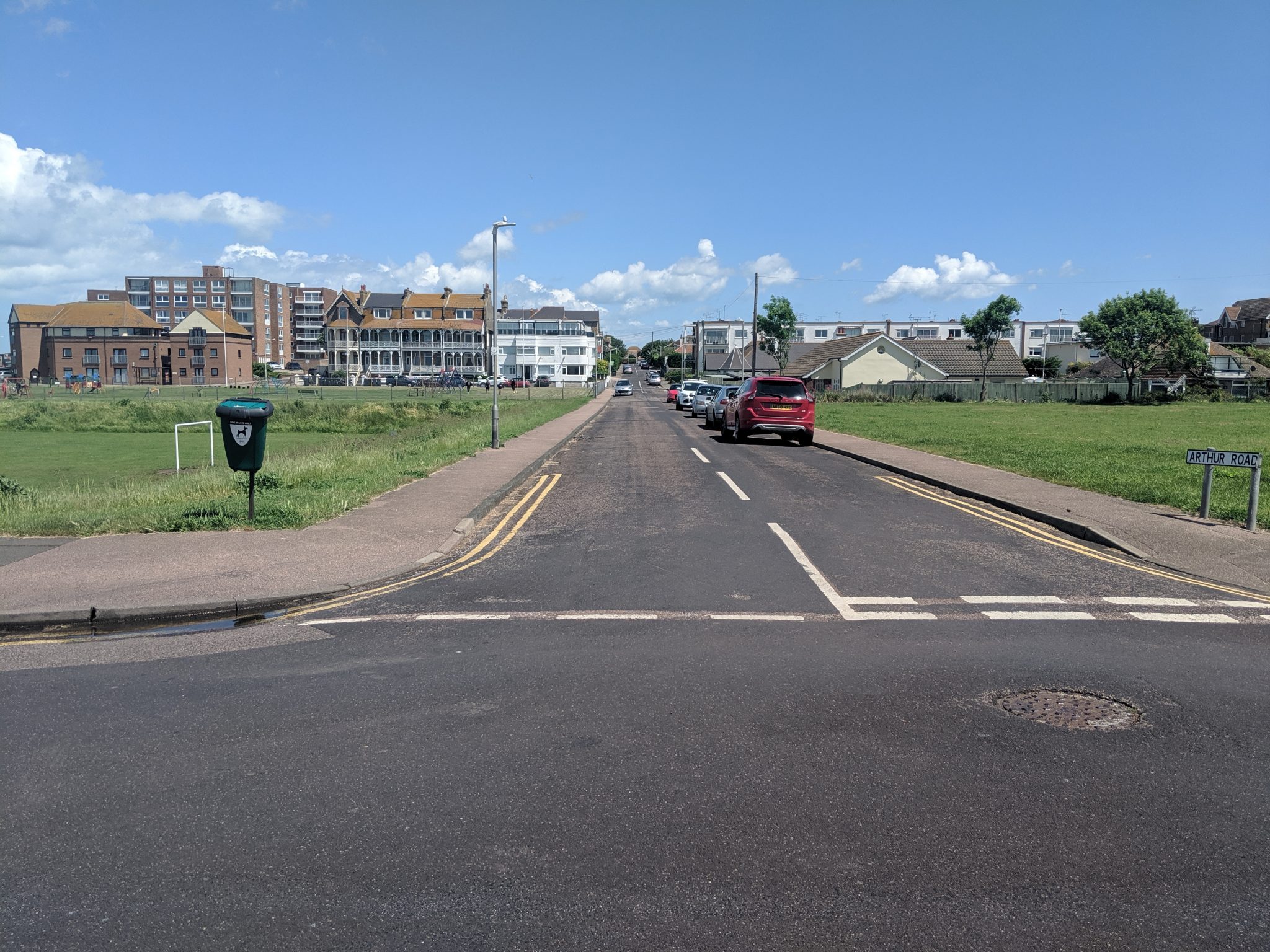 View of the road between the green areas leading to residential properties