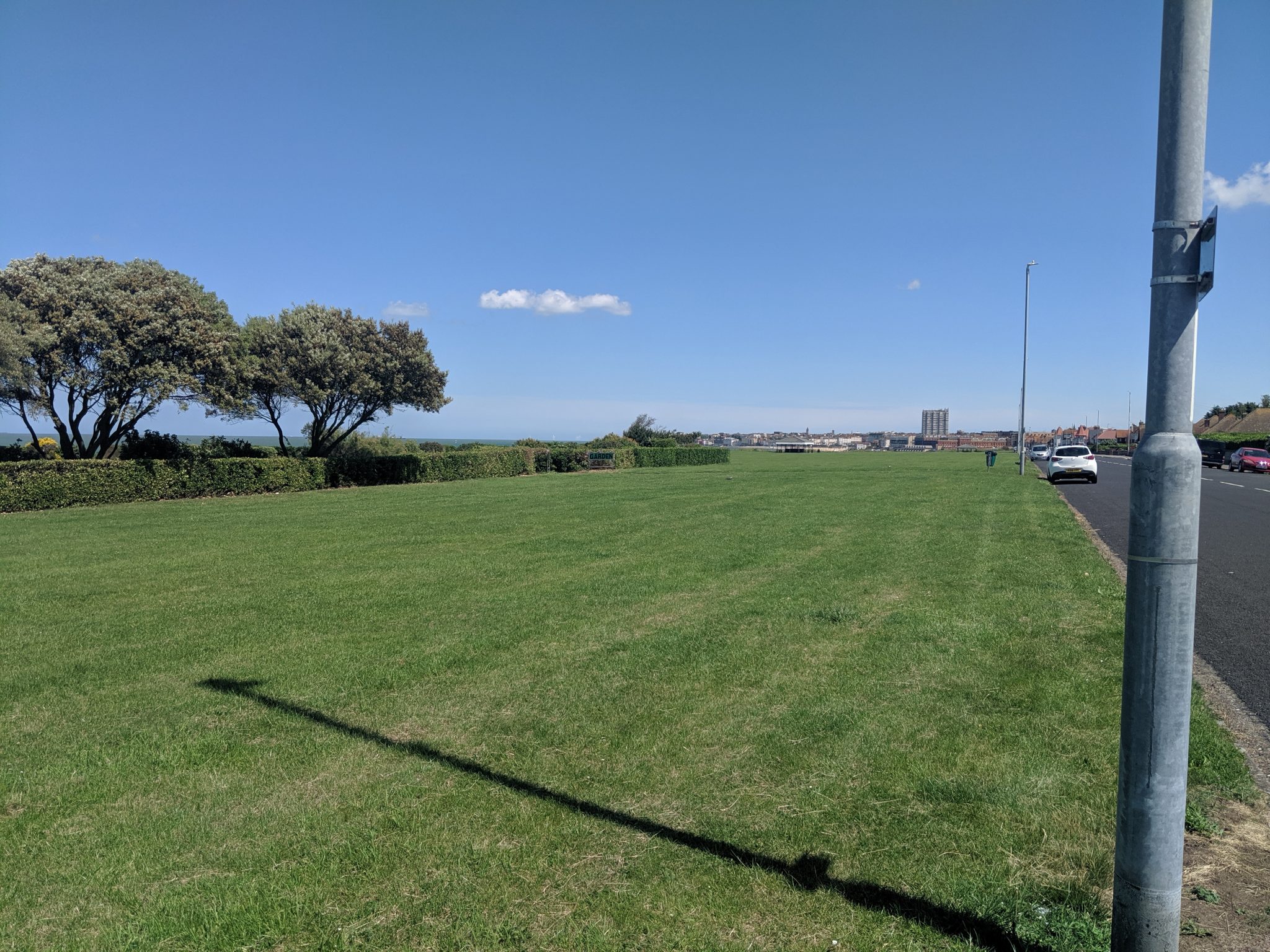 Large green open space alongside a coastal road