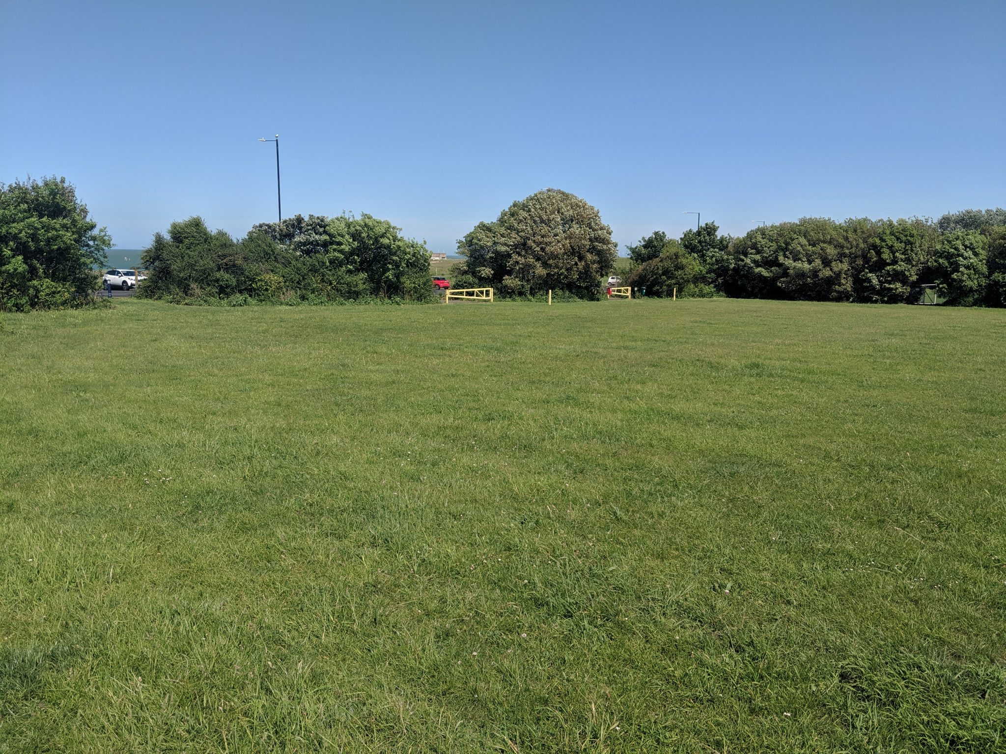 Large green open space area leading to parking area