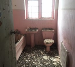 A pink bathroom suite including bath, sink and toilet that needs renovating.