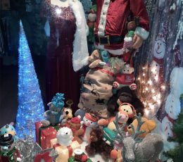 A shop window with a model of Santa, cuddly toys and a glowing Christmas tree