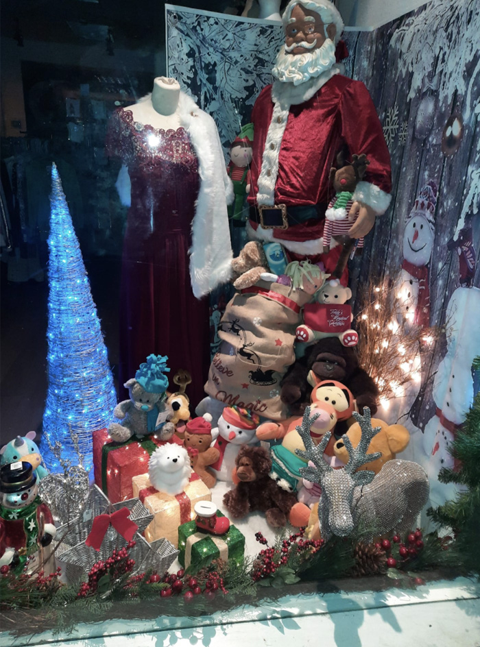 A shop window with a model of Santa, cuddly toys and a glowing Christmas tree