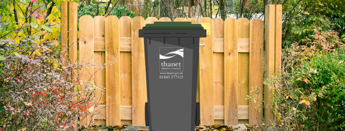 A Thanet District Council garden waste bin placed in front of a gate. There are plants either side of the gate.