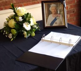 The Book of Condolence with a framed picture of The Queen and floral tribute