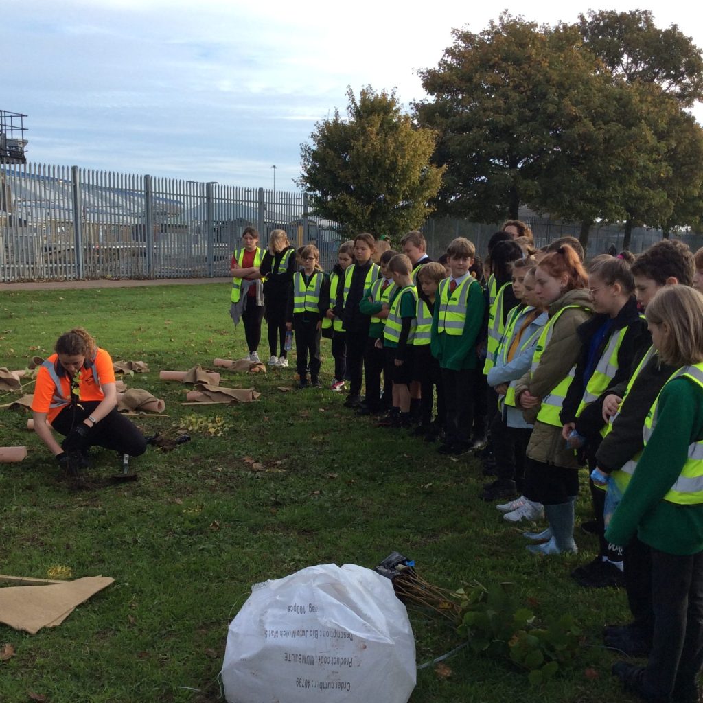 Thanet District Council's Community Tree Planting Coordinator demonstrating how to plant a young tree to the children