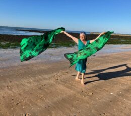 Women arabian dancing on the beach waving bight green material blowing in the breeze
