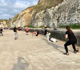 Mixed group of adults doing keep fit activities on the lower promenade at Walpole Bay including squats