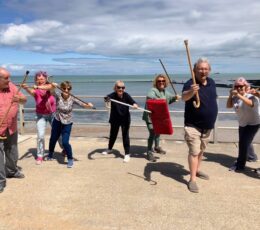 Mixed group of older adults with batons taking part in martial arts on the lower promenade at Walpole Bay