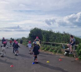 Group of mixed age children scooting between cones on promenade area