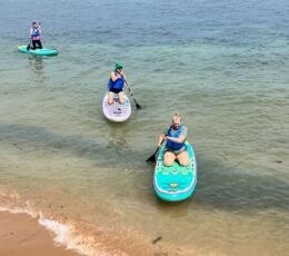 3 people on stand up paddleboards in the sea paddling into the shore
