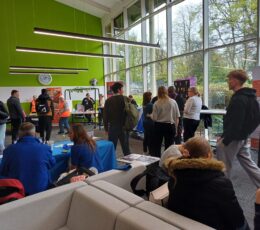 Interior of Welcome Building at EKC Broadstairs College. Young people walking around stalls and talking.