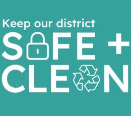 Keep our district safe and clean in white text on teal background the A in safe is the line drawing of a padlock and the A in clean is the line drawing of a recycling symbol