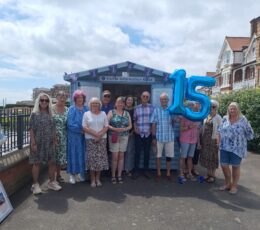 Visitor Ambassadors standing outside Broadstairs Information Kiosk, holding balloons to represent 15.