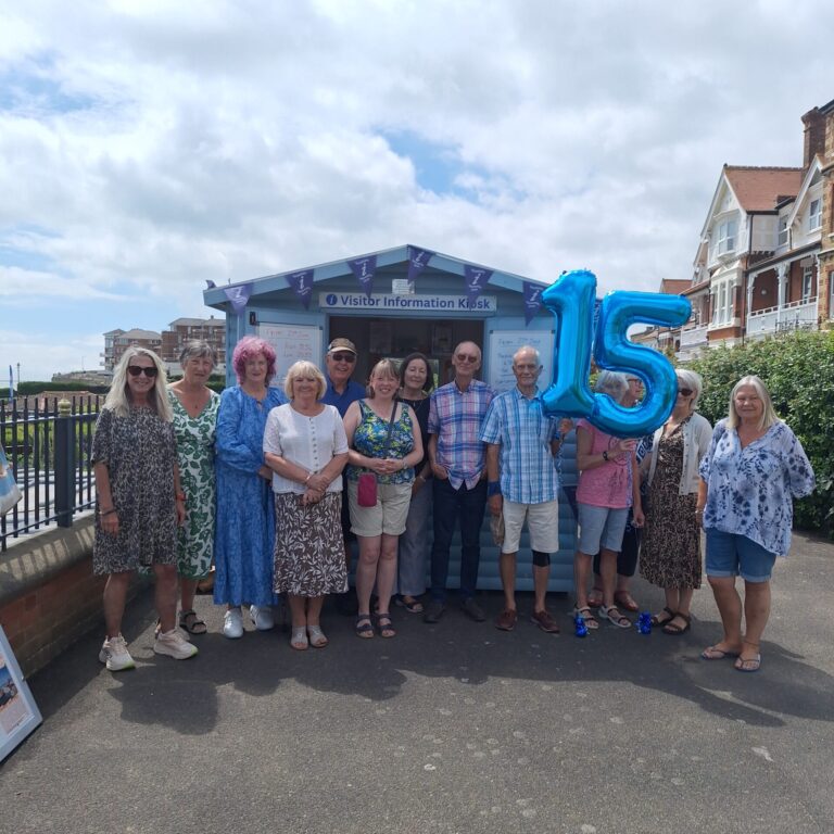Visitor Ambassadors standing outside Broadstairs Information Kiosk, holding balloons to represent 15.