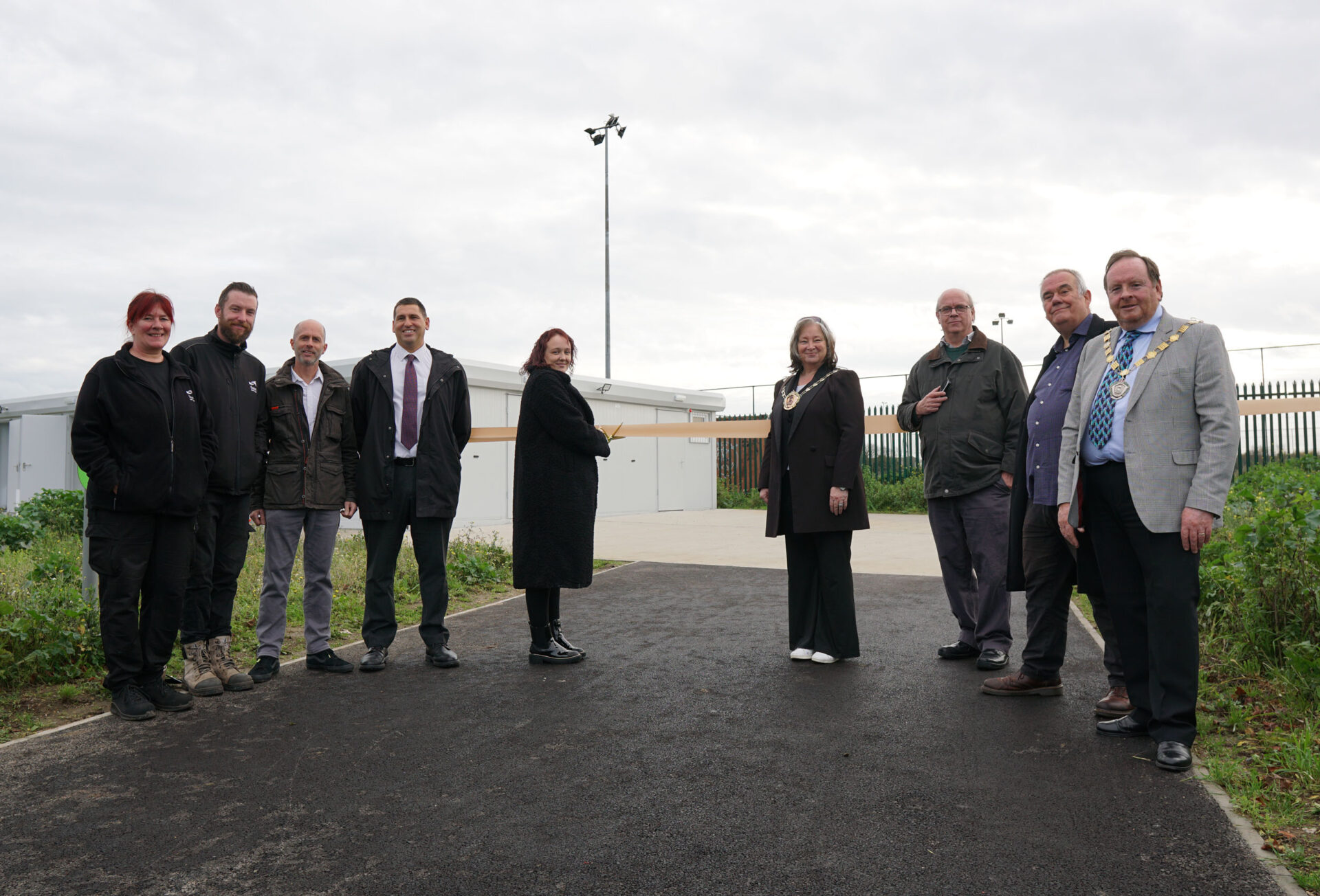 Councillors and council officers standing in front of the new pavilion at Jackey Bakers, about to cut the ribbon.