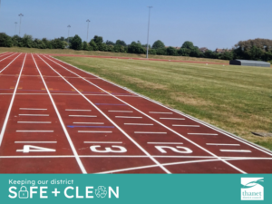 An outdoor running track under a clear blue sky, featuring white lane markings.