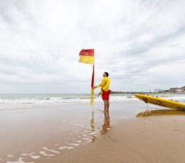 RNLI Senior lifeguard moving a red and yellow flag at Margate Main Sands, Kent.
