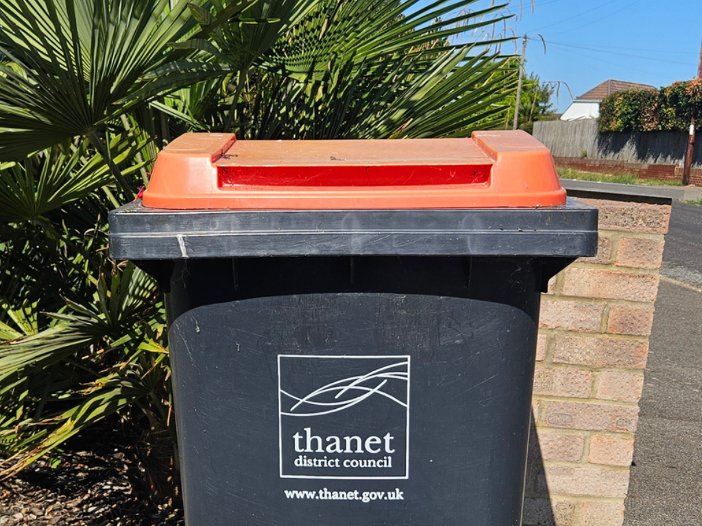 Black wheelie bin with a red lid. Printed white logo and text read Thanet District Council and www.thanet.gov.uk
