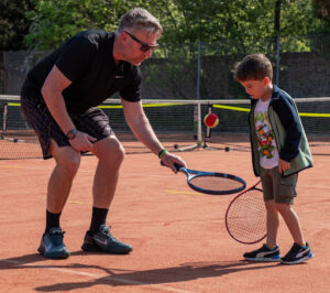 A man and young boy playing tennis