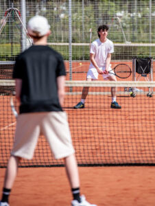 Two young people playing tennis